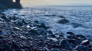 A rocky shoreline with waves crashing onto the rocks, a clear sky, and distant mountains. - An Oceanfront Cottage with Stunning Views and Direct Beach Access (Shirley)