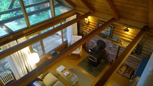 A cabin with a wooden interior, a fireplace, and a dining area with a table and chairs. - An Oceanfront Cottage with Stunning Views and Direct Beach Access (Shirley)