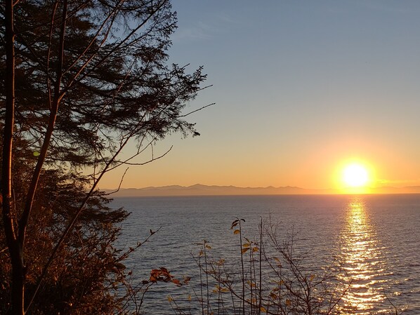 Un tramonto su un corpo d'acqua tranquillo, con montagne sullo sfondo.