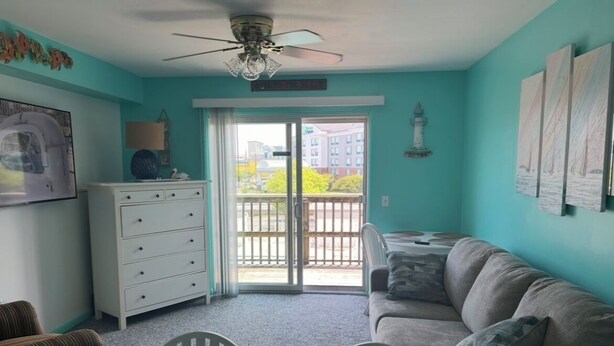 Ein Zimmer mit Türkiswänden, einem grauen Sofa, einer weißen Kommode und einem Deckenventilator.