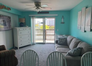 A room with teal walls, a gray sofa, a white dresser, and a ceiling fan. - Beach Days & Bay Sunsets. Your Easy OCMD Escape! Raffles Unit 339 N (Ocean City)