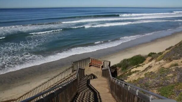 A wooden boardwalk leading to a beach with waves crashing onto the shore. - Carlsbad Beach Resort- Across Street from Crystal Blue Beaches. (Carlsbad)