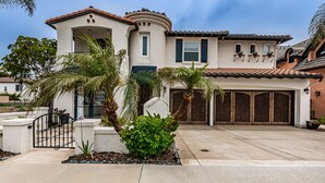 A two-story house with a garage, palm trees, and a concrete driveway. - Carlsbad Beach Resort- Across Street from Crystal Blue Beaches. (Carlsbad)