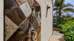 A shower area with a stone tile wall and a tiled floor leading to a garden. - Carlsbad Beach Resort- Across Street from Crystal Blue Beaches. (Carlsbad)