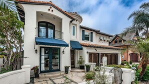 A two-story house with a balcony, a covered entryway, and a garden with potted plants. - Carlsbad Beach Resort- Across Street from Crystal Blue Beaches. (Carlsbad)