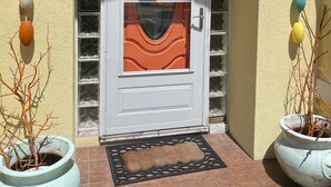 A building entrance with a white door, a sign reading "COTTAGE," and decorative elements like hanging ornaments and potted plants. - 10% discounts Aug, Sept  (St Augustine)