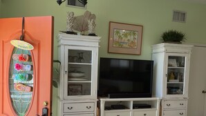 A living room with a television, white cabinets, a decorative door, and a ceiling light fixture. - 10% discounts Aug, Sept  (St Augustine)