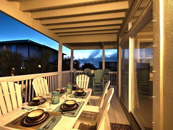 A covered outdoor dining area with a table set for four, surrounded by white Adirondack chairs. - DanielDunes-Spectacular Gulf Views!Private Pool/Steps to Beach/Kayak/SUP/EXTRAS (Santa Rosa Beach)