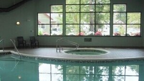 An indoor swimming pool with a view of trees and a house through large windows. - Pet Friendly 2 bedroom plus loft, in Parksville's beautiful resort area (Parksville)