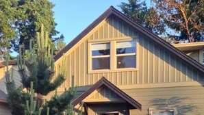A two-story house with a front porch, a garage, and a small front yard with a tree and a potted plant. - Pet Friendly 2 bedroom plus loft, in Parksville's beautiful resort area (Parksville)