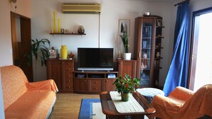Ein Wohnzimmer mit einer Couch, einem Couchtisch, einem Fernseher und einem Schrank.