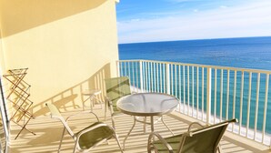 Een balkon met een tafel, stoelen, een droogrek en uitzicht op de oceaan.