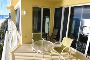 Ein Balkon mit Tisch und Stühlen mit Blick auf Strand und Meer.