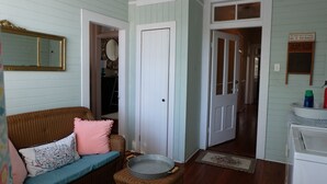 A room with a wicker sofa, a metal tray, and a door leading to another room. - "The Stella" Vintage Fun & Artsy Victorian w/ Parking = Family & Friends Getaway (Savannah)
