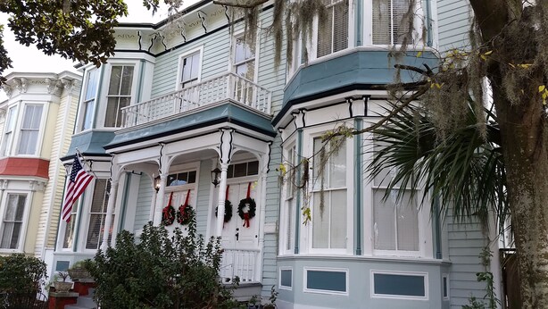 A historic building with bay windows, a porch with American flags, and Christmas wreaths. - "The Stella" Vintage Fun & Artsy Victorian w/ Parking = Family & Friends Getaway (Savannah)