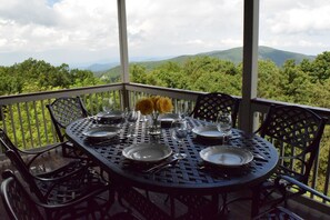 A round table set for dining with chairs, a vase with yellow flowers, and a scenic view of mountains and trees. - Book Now for Spring and Summer....Awesome Views and 5-Star Amenities (Roseland)