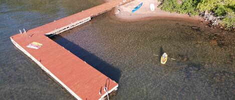 A wooden pier extending into a clear river, with a small boat anchored nearby.