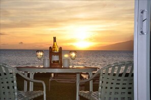 Ein Tisch mit zwei Gläsern und einer Flasche, vor einer Sonnenuntergangsansicht.