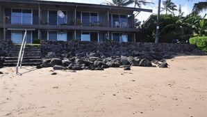 A beachfront hotel with a stone wall and steps leading to the entrance. - Pikake - West Maui Beachfront Condo! 20 Feet from the Ocean! (Lahaina)