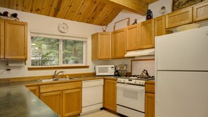 Une cuisine avec des meubles de rangement en bois, une cuisinière, un four à micro-ondes et un réfrigérateur.