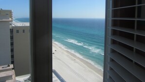 A view of a beach from a window with a view of the ocean and a building in the background. - Beautiful Majestic Beach Towers Resort #2109  (Panama City Beach)