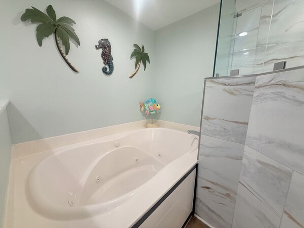 Un baño con bañera, cabina de ducha de vidrio y decoración en la pared.