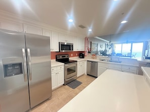 A modern kitchen with stainless steel appliances, white cabinetry, and a large island.