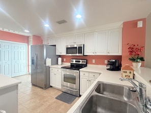A modern kitchen with white cabinets, stainless steel appliances, and a sink.
