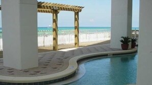 An indoor swimming pool with a wooden pergola and a view of the beach. - Beautiful Majestic Beach Towers Resort #2109  (Panama City Beach)