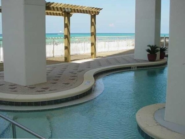 Ein Innenpool mit einer Holzpergola und Blick auf den Strand.