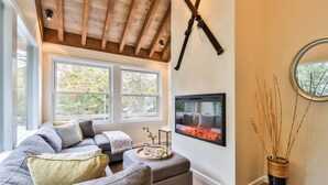 Una sala de estar moderna con un amplio sofá seccional gris, techo de madera y chimenea.