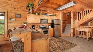 A wooden cabin interior with a kitchen, bar area, and a staircase. - Broken Spoke is a great cabin with an awesome View (Sevierville)