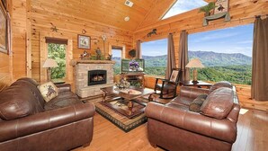 A cozy log cabin interior with leather sofas, a fireplace, and a scenic mountain view. - Broken Spoke is a great cabin with an awesome View (Sevierville)