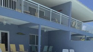 Una piscina con solarium bianco e una veranda coperta con sedie e un tavolo.