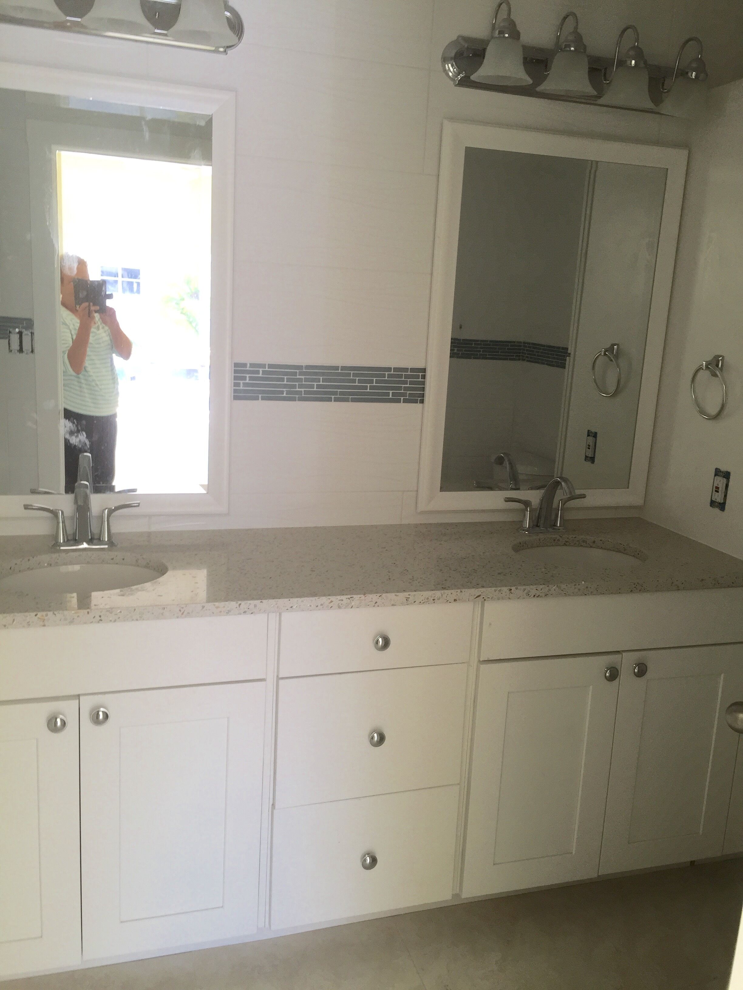 A bathroom with a large mirror, two sinks, and a vanity with drawers.