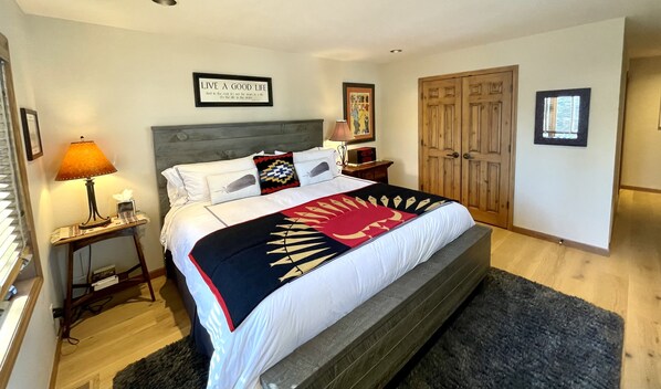 Una cama bien tendida con un edredón estampado, una lámpara de noche y una cita inspiradora en un marco en la pared.