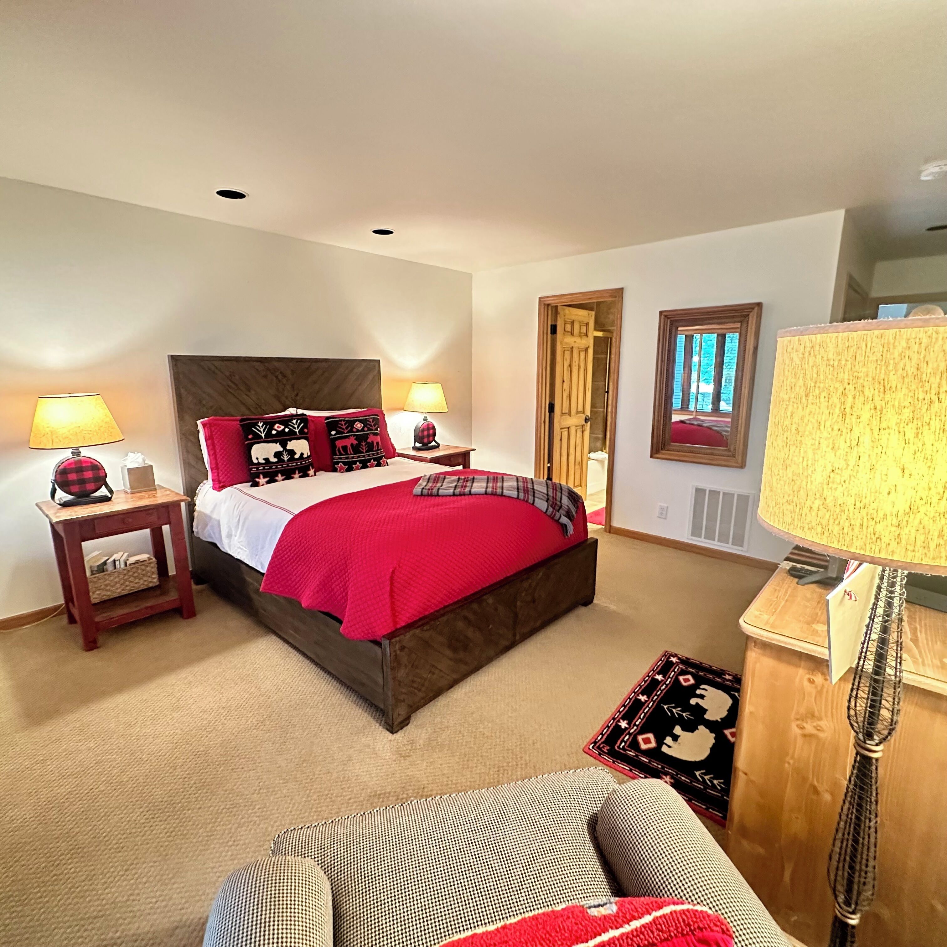 Une chambre à coucher avec un grand lit, deux tables de chevet, une commode, une chaise et une lampe.