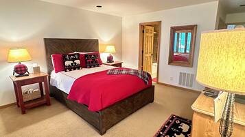 Une chambre à coucher avec un grand lit, deux tables de chevet, une commode, une chaise et une lampe.