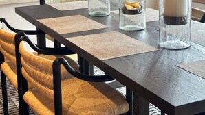 A dining table with three glass candle holders, a framed deer picture, and a woven chair. - Exclusive Teton Pines Home off Teton Village Rd. 5 min from Teton Village Skiing (Wilson)