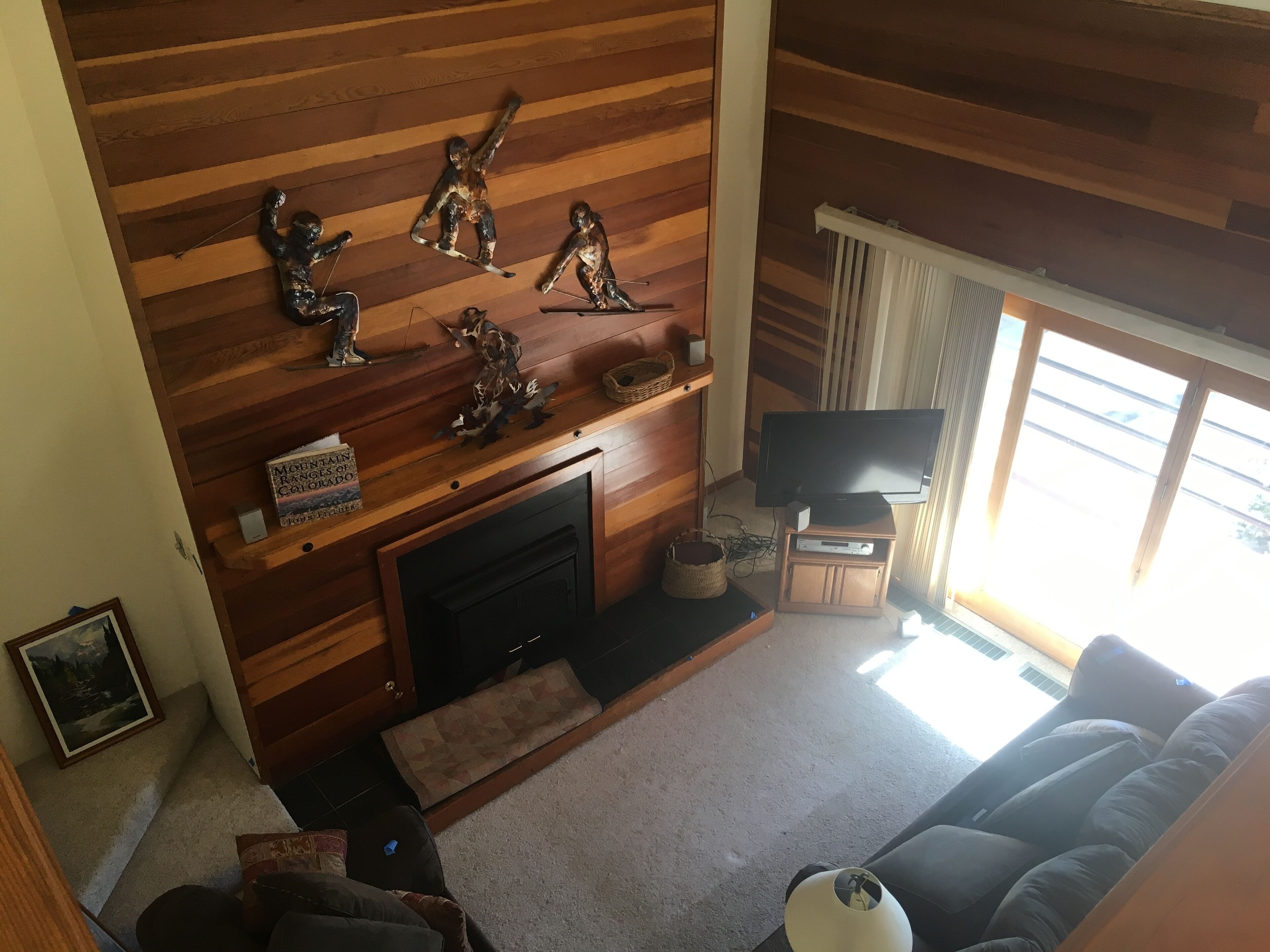 A living room with a fireplace, wooden panel walls, a television, and a couch.