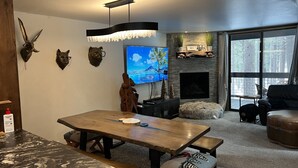 A modern living room with a wooden dining table, a flat-screen TV, and decorative animal heads on the wall. - walking distance to skiing and nightlife in Northstar resort (Truckee)