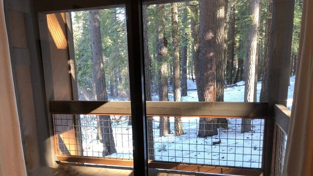 A wooden deck with a metal railing overlooking a snowy forest. - walking distance to skiing and nightlife in Northstar resort (Truckee)