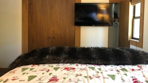 A bedroom with a bed, a wooden wardrobe, and a mounted TV. - walking distance to skiing and nightlife in Northstar resort (Truckee)