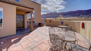 A patio with a round metal table and chairs, a door, and a view of mountains. - High End Southwest Luxury, Spa-like Baths, Steam Shr, Sauna, Garage,Pool,Hot Tub (Moab)