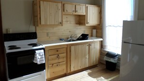 A kitchen with wooden cabinets, a stove, a sink, and a refrigerator.