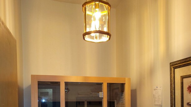 A room with a wooden wardrobe, a hanging light fixture, and a framed picture on the wall.