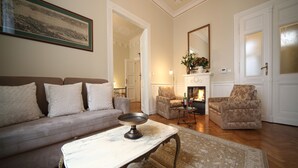 A living room with a sofa, armchairs, a coffee table, and a fireplace.