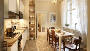 A kitchen with a dining area, featuring a tiled floor, wooden cabinets, and a chandelier.