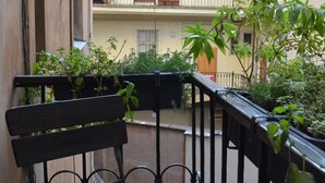 A balcony with a wooden bench and potted plants.
