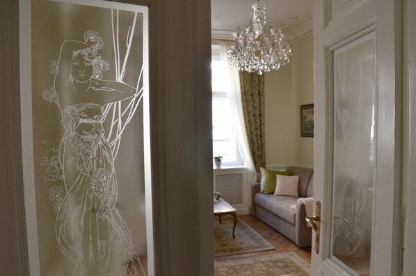 A room with a sofa, a chandelier, and a decorative wall panel.